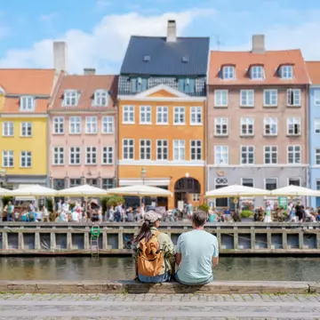 A couple sits on a wall by the water in Copenhagen, Denmark