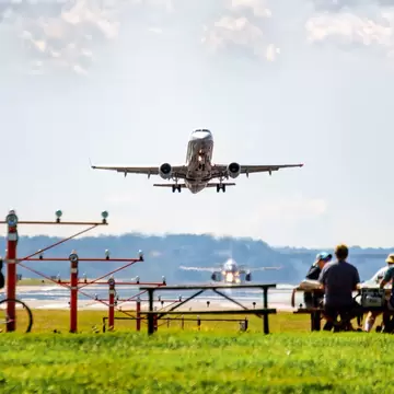 People sat at a viewpoint as a plane takes off from a nearby runway: Ronald Reagan Washington National Airport, USA