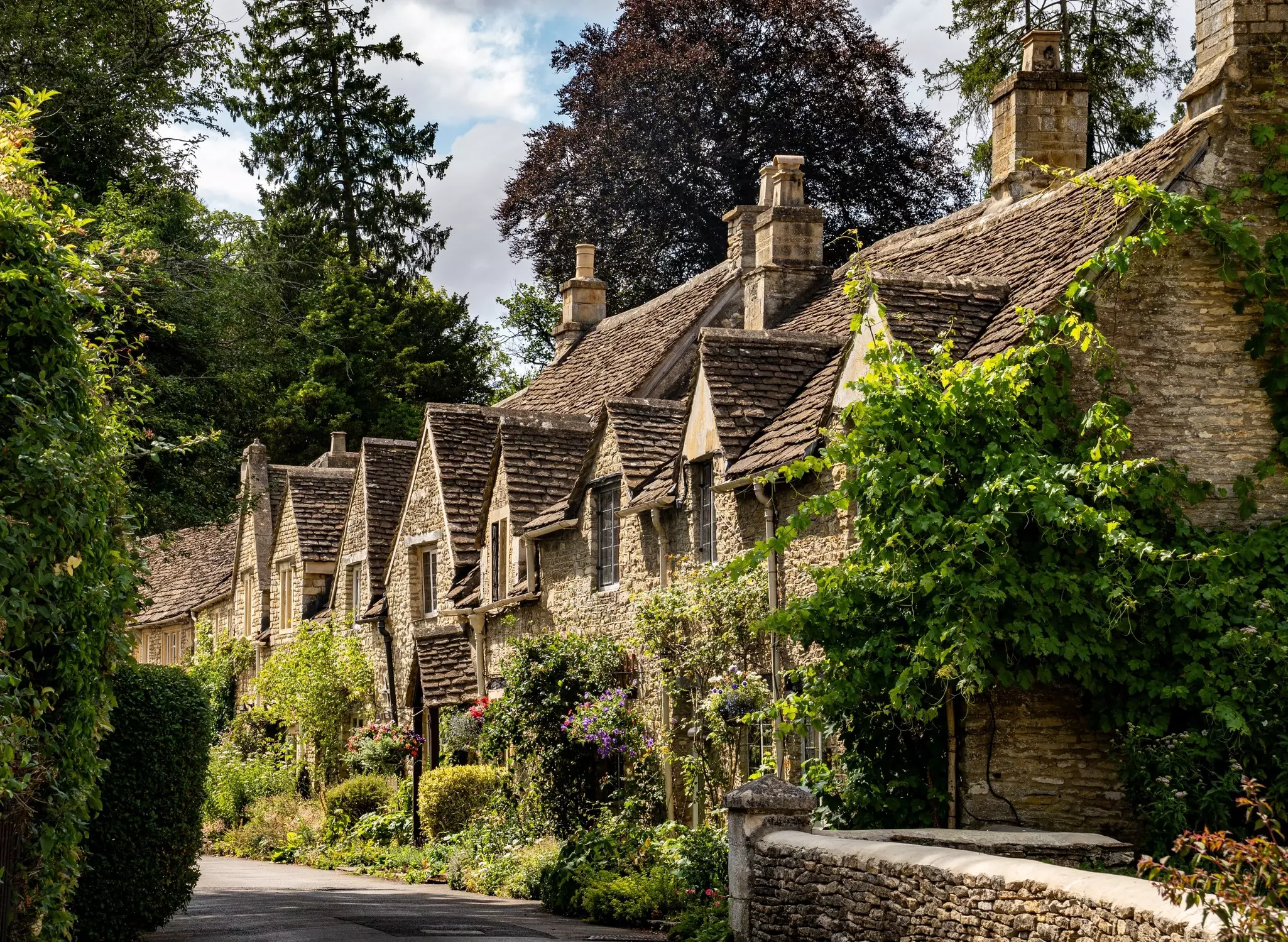 Stone structures with peaked roofs on a road in sunshine.
