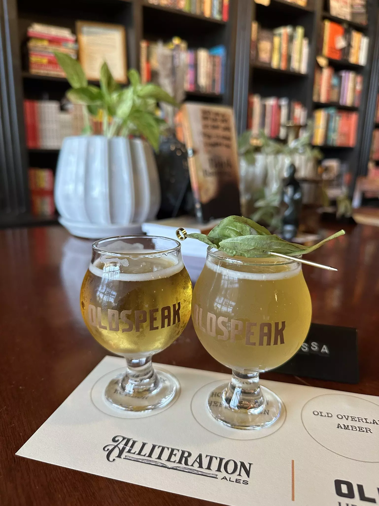 Two small glasses of beers in front of a bookcase