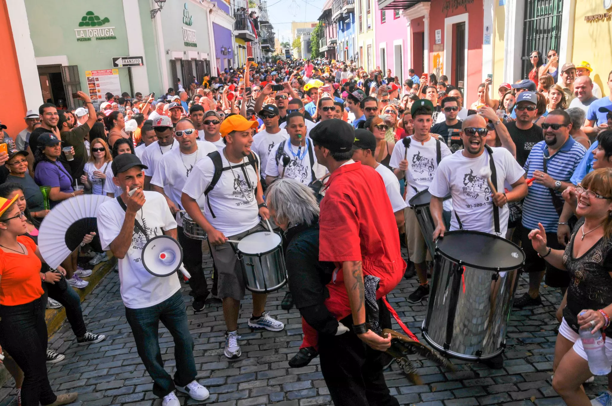 Large group celebrates on the street with megaphones and drums
