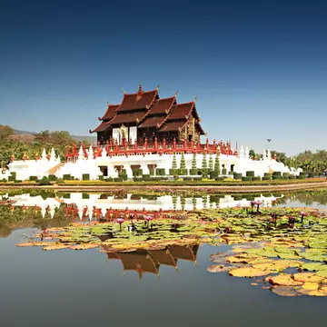 Royal Pavilion (Ho Kum Luang) Lanna style pavilion in Royal Flora Rajapruek Park botanical garden, Chiang Mai, Thailand. Reflection of pavilion in water, surrounded by lilly pads.