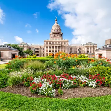 The Texas State Capitol with flower garden. It was completed in 1888 in Downtown Austin. It contains the offices and chambers of the Texas Legislature and the Office of the Governor.