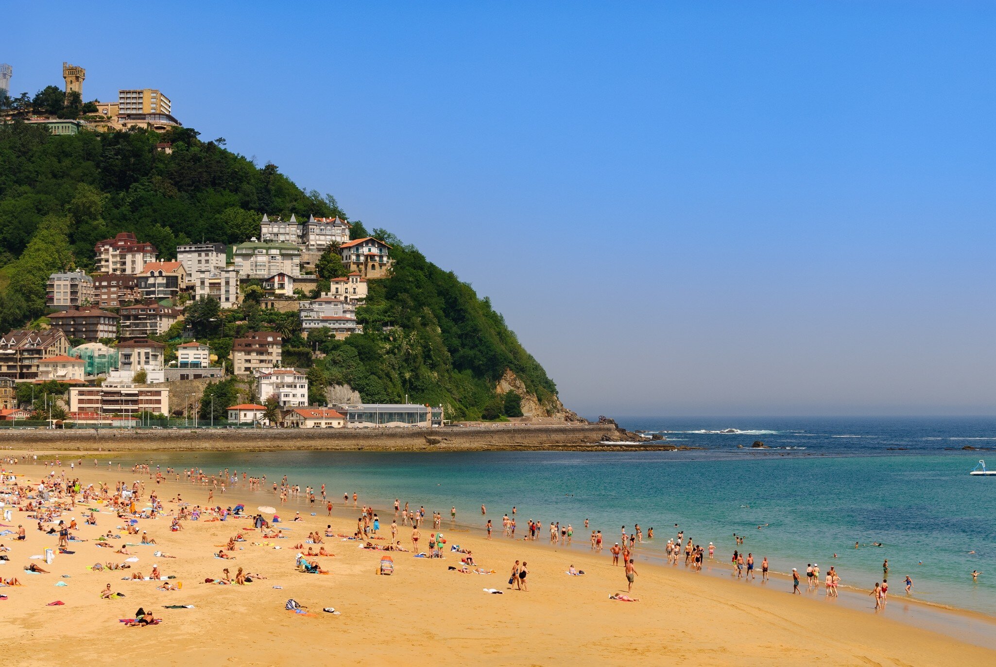 View of people swimming and tanning on Playa de Ondarreta in San Sebastián, Spain.