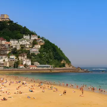 View of people swimming and tanning on Playa de Ondarreta in San Sebastián, Spain.