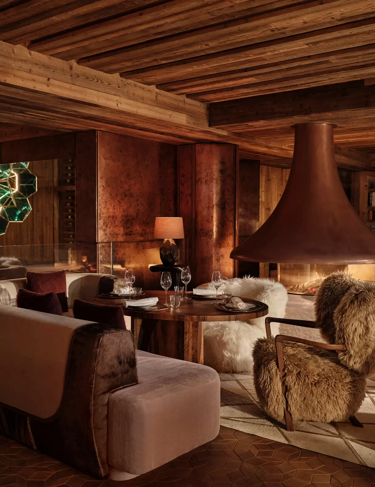 A cozy restaurant with dark furnishings and fluffy upholstery. SALTO at Rosewood Courchevel
