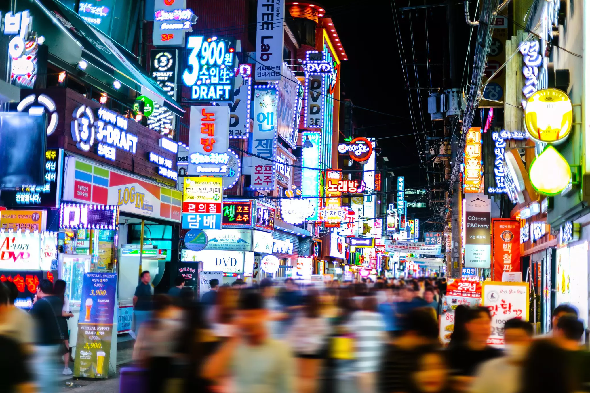 Neon sights lit up at night in Hongdae in Seoul, South Korea, with a blurred crowd