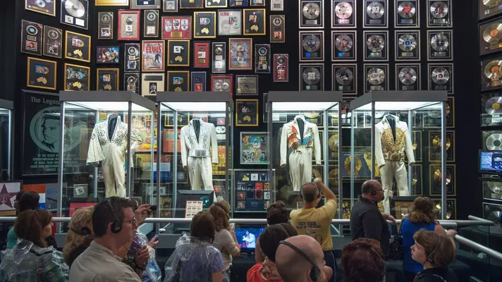 Four outfits worn by Elvis in glass boxes in an exhibit.