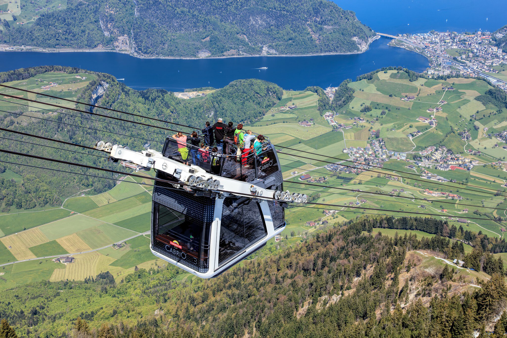 Stans, Switzerland - 7 May, 2016: people in a gondola of the Stanserhorn Cabrio cable car. Stanserhorn Cabrio is the the world's first double deck open top cable car, it carries 60 passengers per cabin with room for 30 on the open deck. Stanserhor...