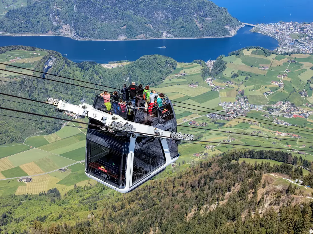Stans, Switzerland - 7 May, 2016: people in a gondola of the Stanserhorn Cabrio cable car. Stanserhorn Cabrio is the the world's first double deck open top cable car, it carries 60 passengers per cabin with room for 30 on the open deck. Stanserhor...