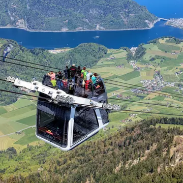 Stans, Switzerland - 7 May, 2016: people in a gondola of the Stanserhorn Cabrio cable car. Stanserhorn Cabrio is the the world's first double deck open top cable car, it carries 60 passengers per cabin with room for 30 on the open deck. Stanserhor...