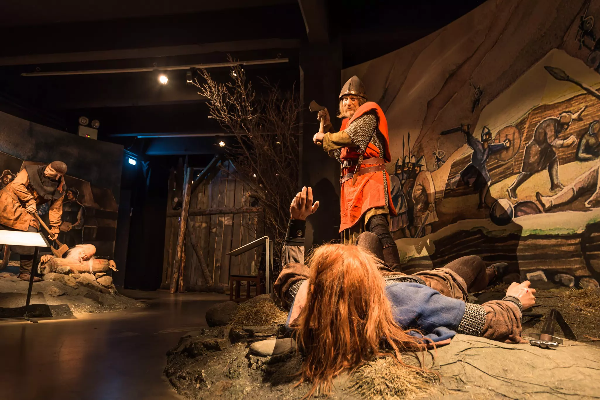 A diorama in a museum showing a Viking about to swipe a person on the floor with an ax.