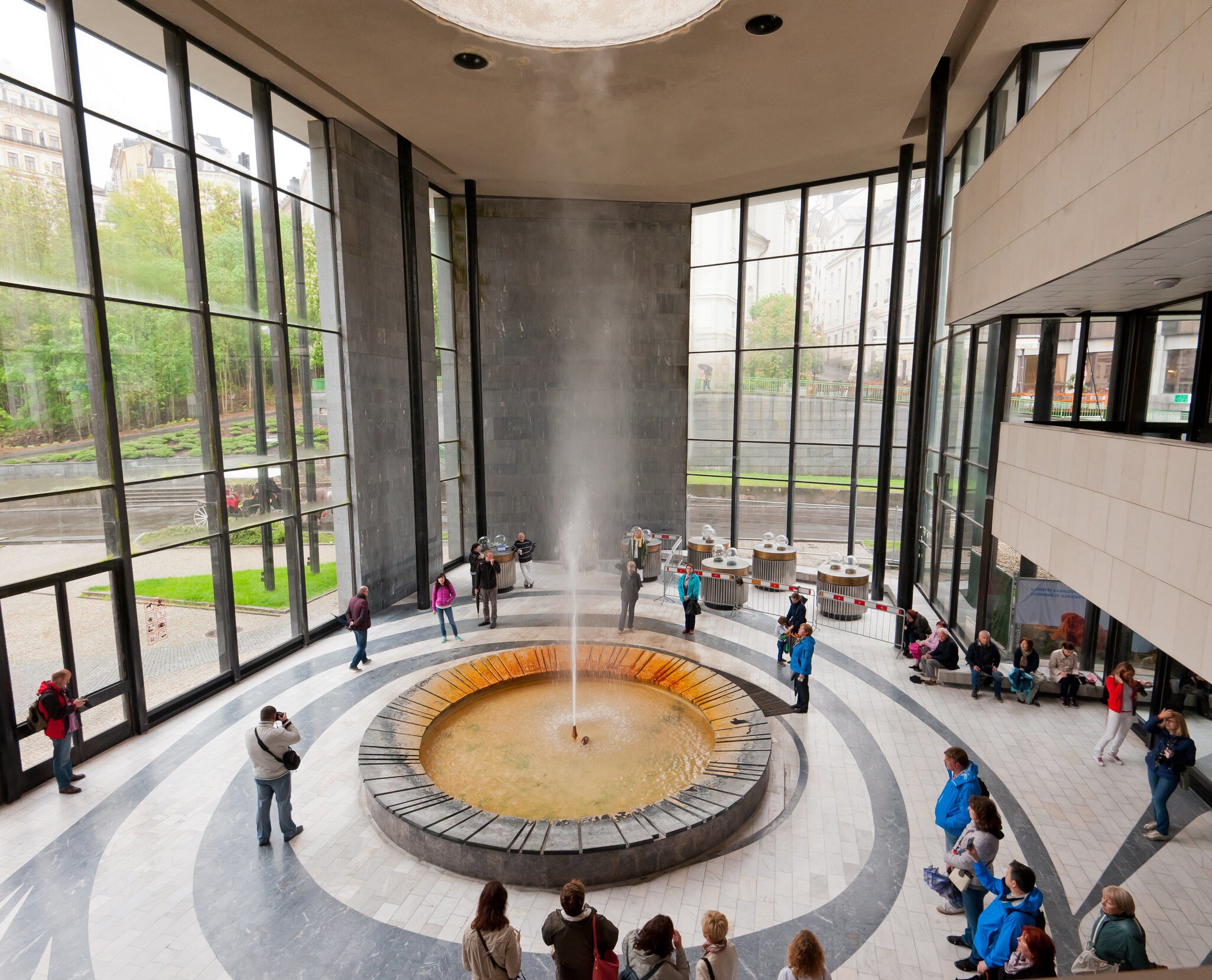 Visitors surround the geyser in the Hot Spring Colonnade. Karlovy Vary, Czech Republic.
