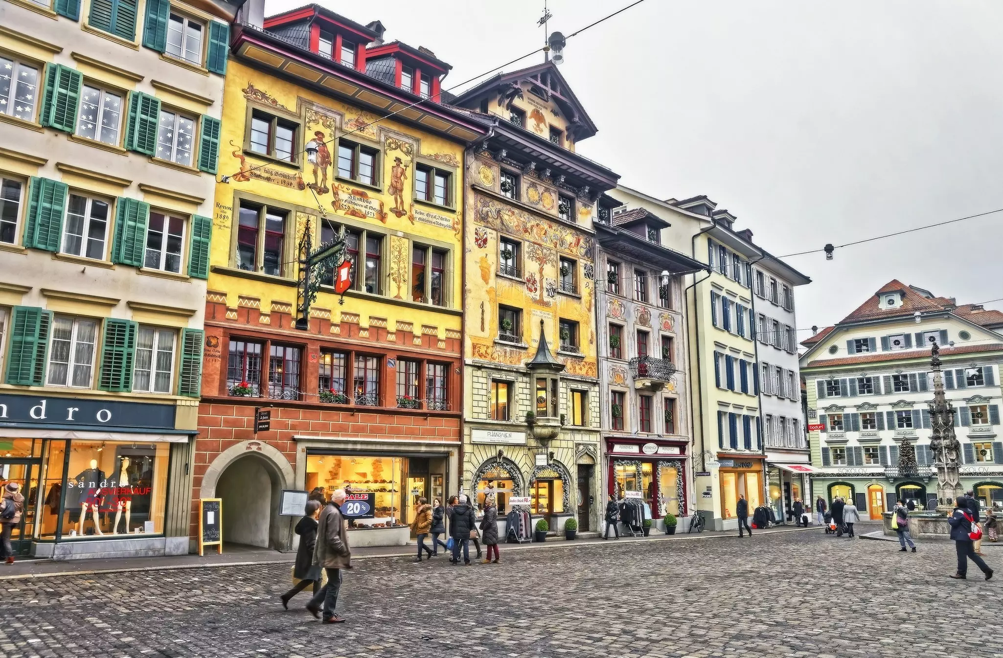 Medieval buildings covered in murals line a city square.