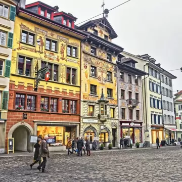 Medieval buildings covered in murals line a city square.