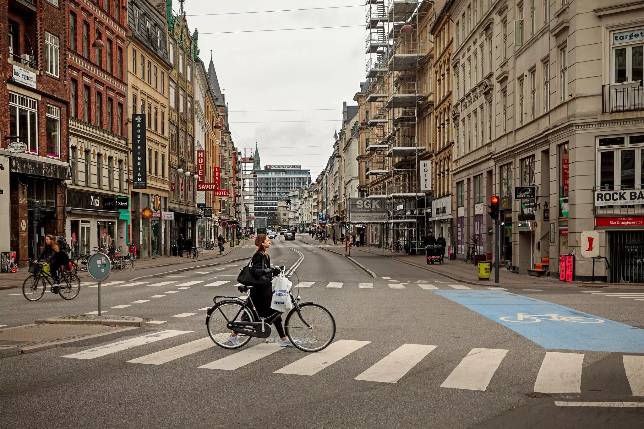 A woman pushing a bicycle along Vesterbrogade in Copenhagen, Denmark