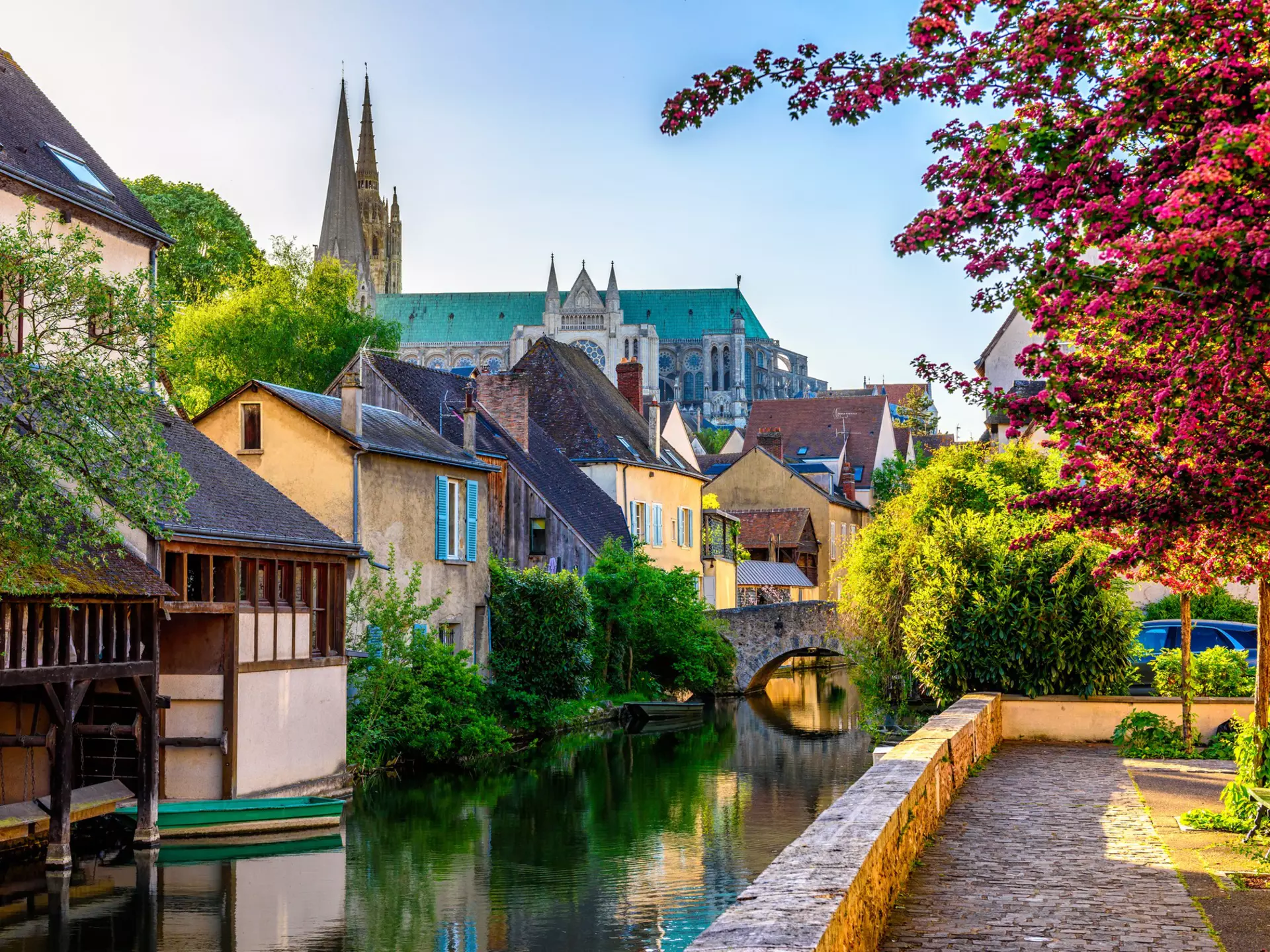 A river embankment with old houses and a cathedral rising above the city.
