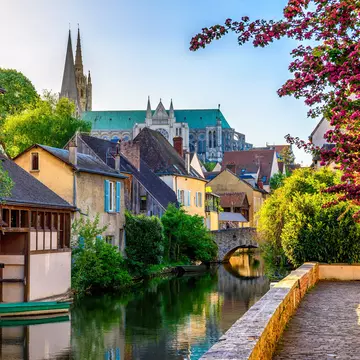 A river embankment with old houses and a cathedral rising above the city.