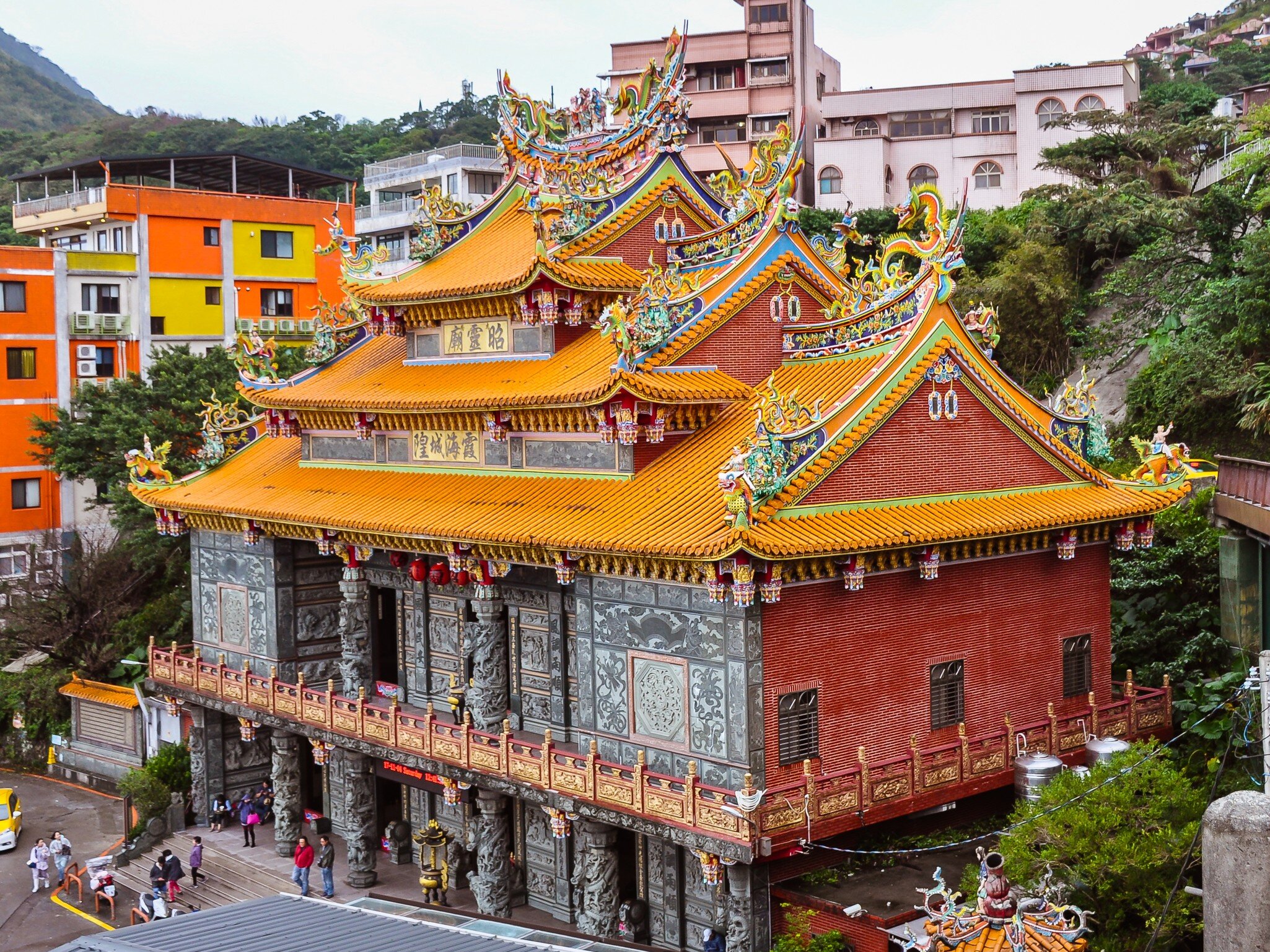 Ornate tiered orange roof and gray columned facade of Fushan Temple in Jiufen, Taiwan.