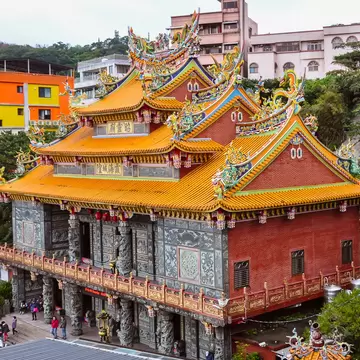 Ornate tiered orange roof and gray columned facade of Fushan Temple in Jiufen, Taiwan.
