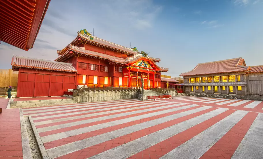 Shuri Castle's vermilion main hall and striped red-and-white courtyard lit at dusk, Naha, Okinawa, Japan