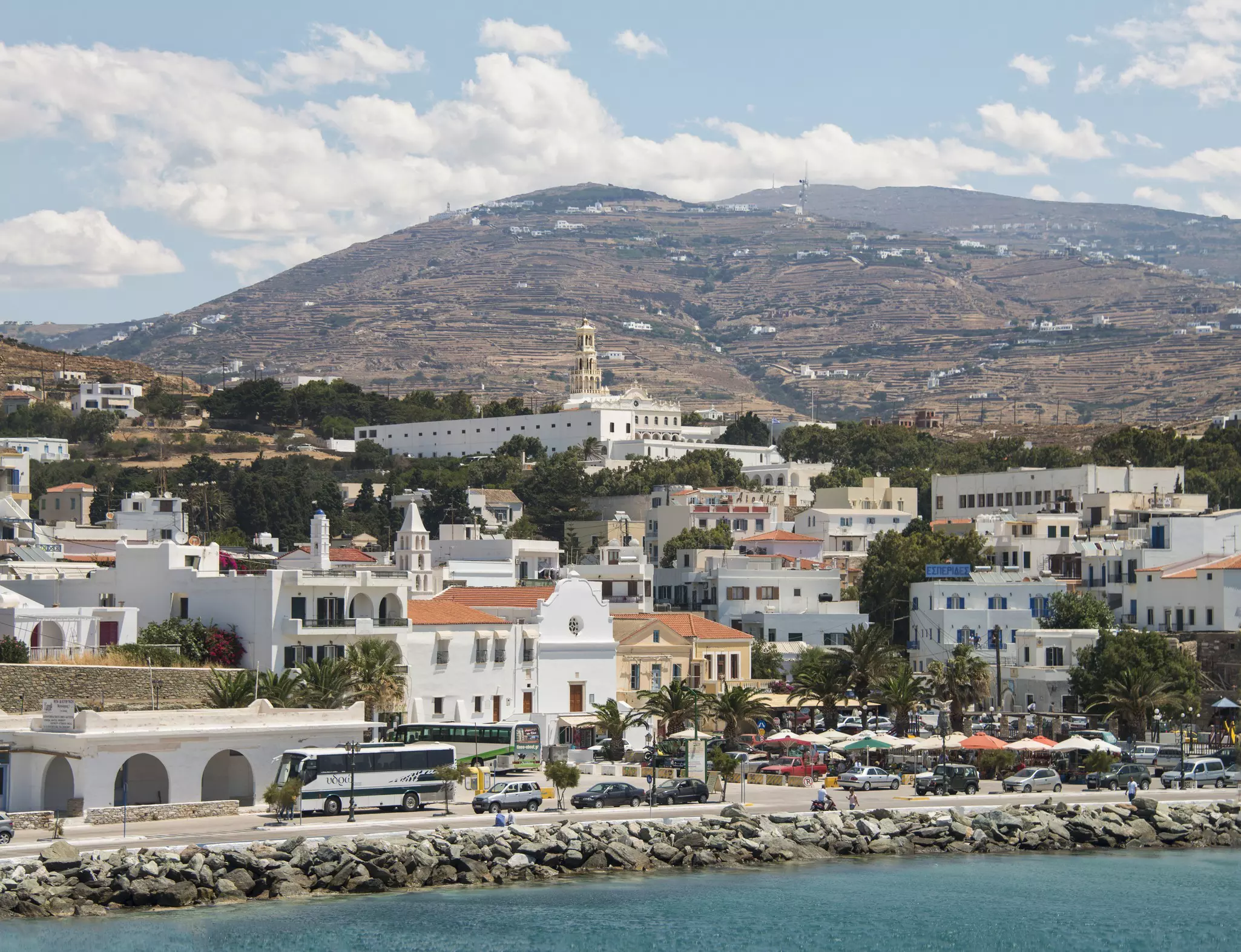 A busy waterfront lined with buses and parked cars.