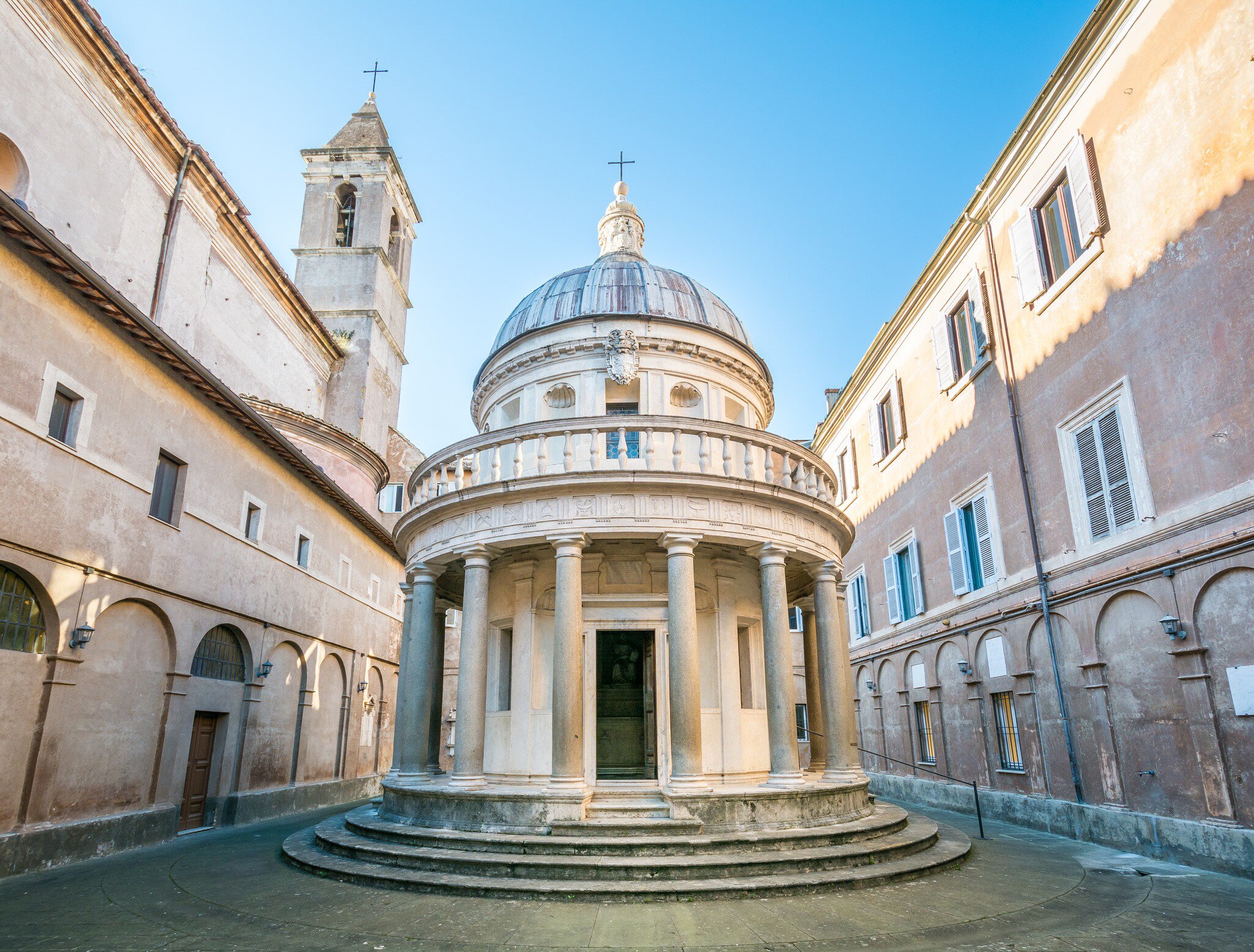 Small circular temple ringed by Doric columns in a narrow courtyard