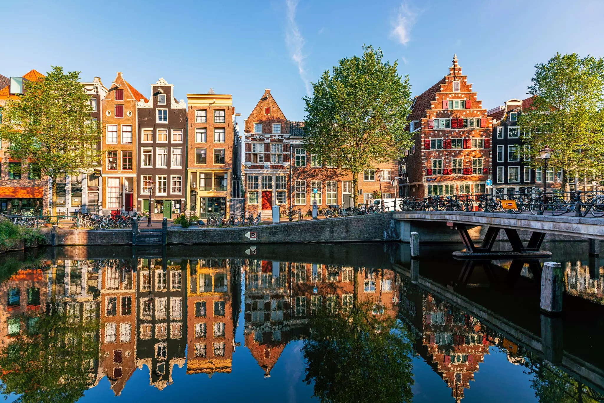 Old historic Dutch houses reflecting in the canal on a sunny day, Amsterdam, Netherlands.