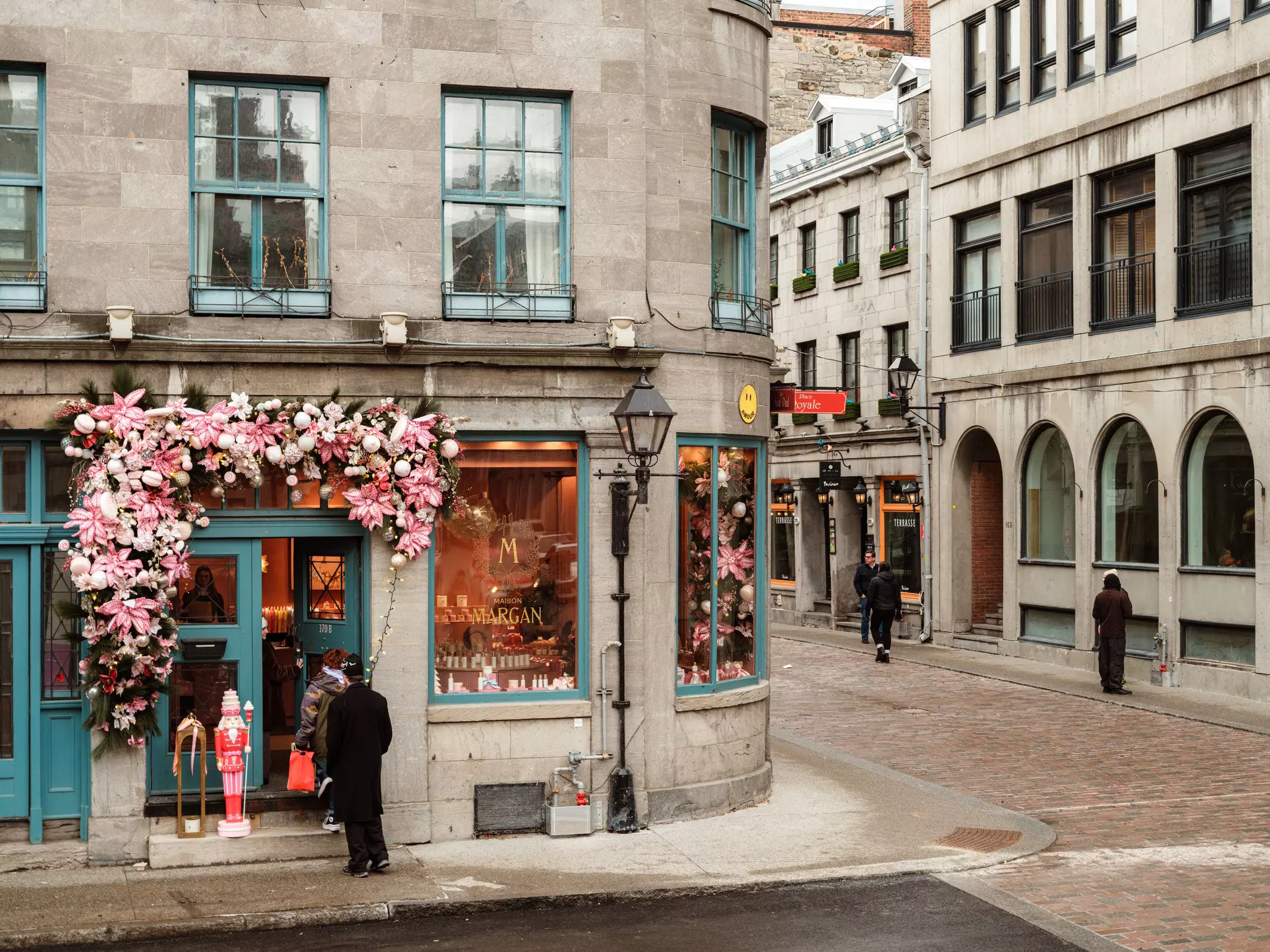 A view of a decorated store on a corner with people in the street wearing jackets