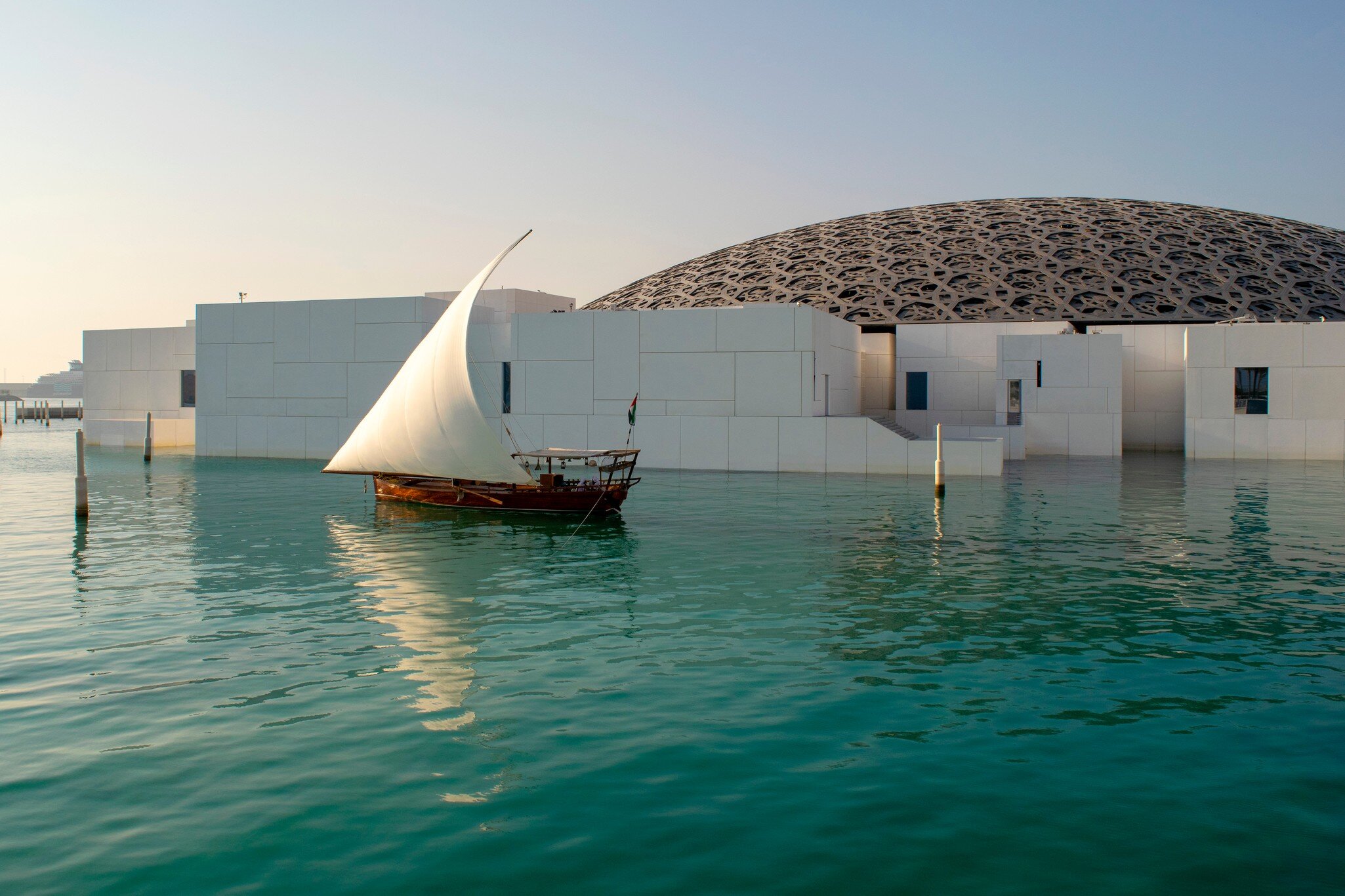 Abu Dhabi / UAE - January 3, 2019: Louvre museum in Abu Dhabi. View of beautiful Louvre exterior with waterfront and wooden sailboat.  License Type: media  Download Time: 2024-02-14T20:05:48.000Z  User: bhealy950  Is Editorial: Yes  purchase_order:   