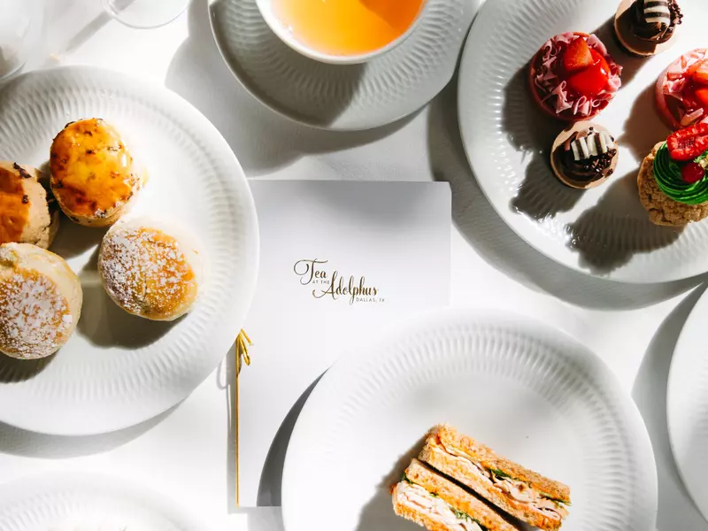 Close-up of cakes on plates and a menu reading "Tea at the Adophus."