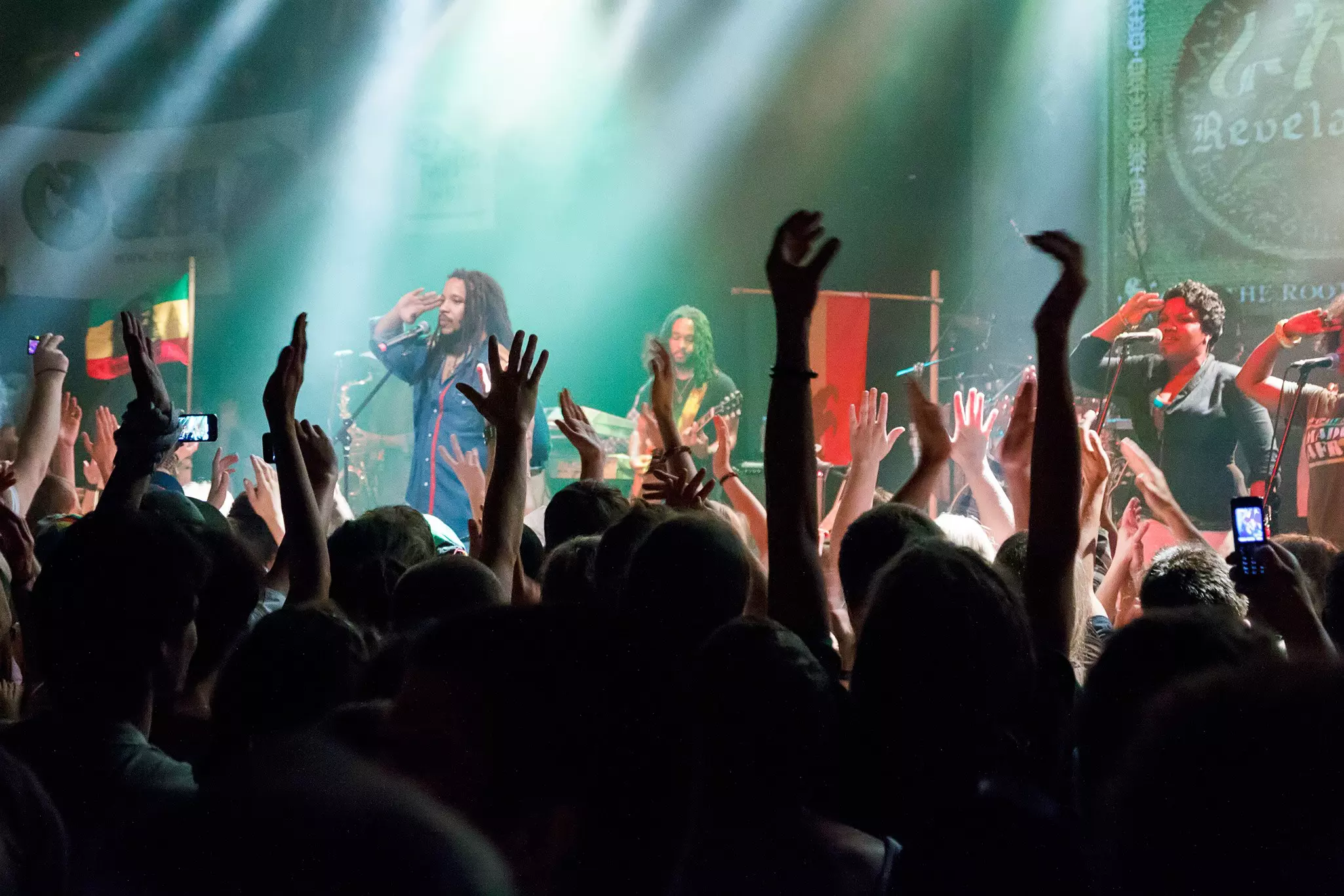 Audience members raise their hands while listening to reggae artist Stephen Marley and his band