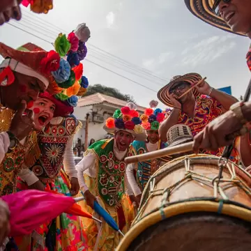 People dance, sing, and play drums in traditional dress.
