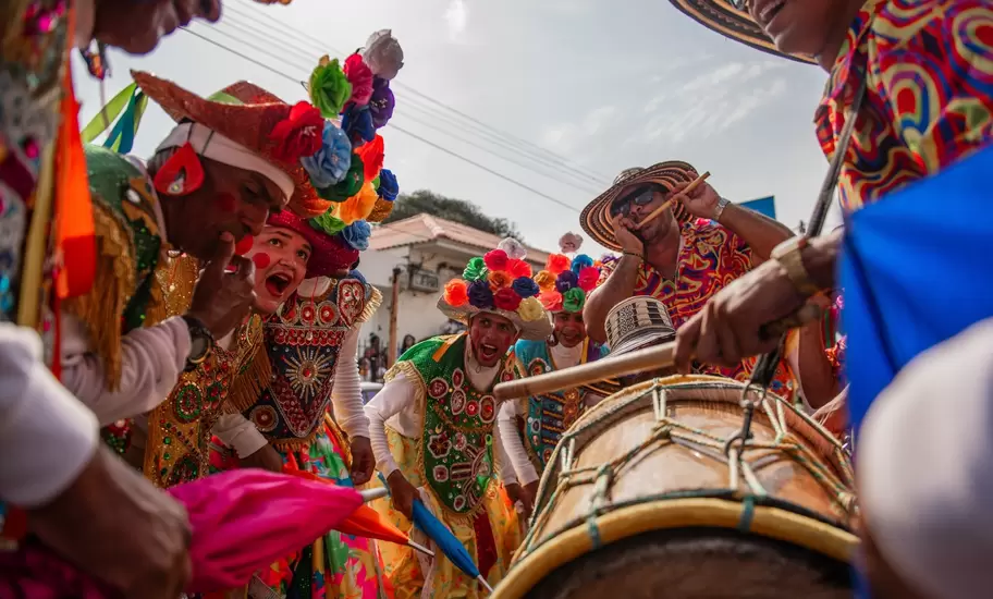 People dance, sing, and play drums in traditional dress.