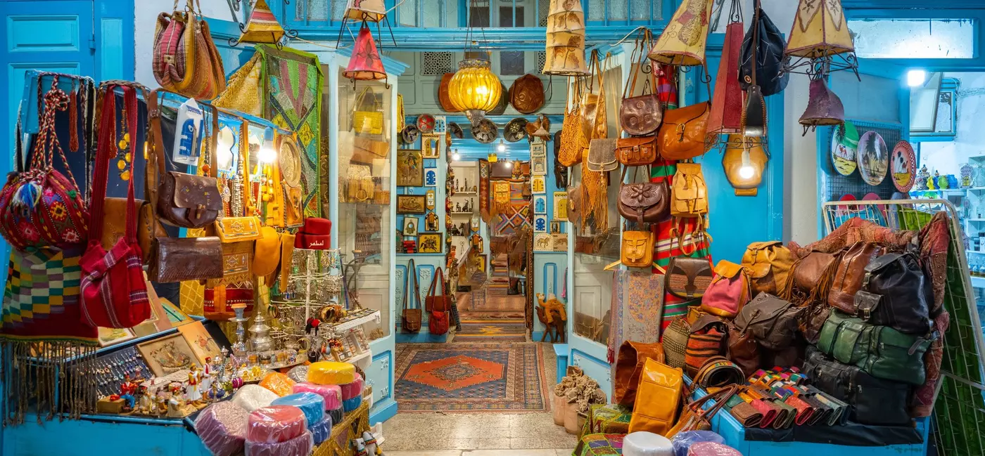 Pottery, textiles and leather goods on sale in a brightly lit shop.