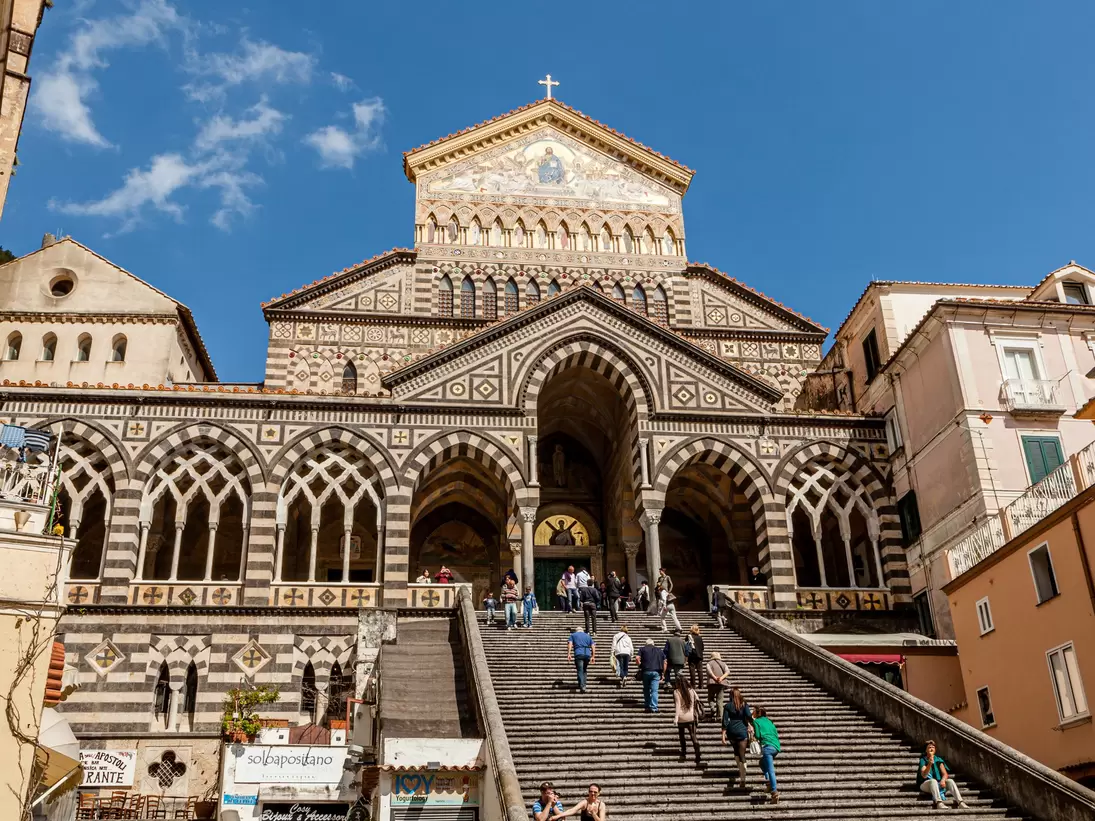 Tourists walk up the steps of the Amalfi Cathedral, known as Cattedrale di Sant'Andrea, and Duomo di Amalfi, in the town of Amalfi, Italy.