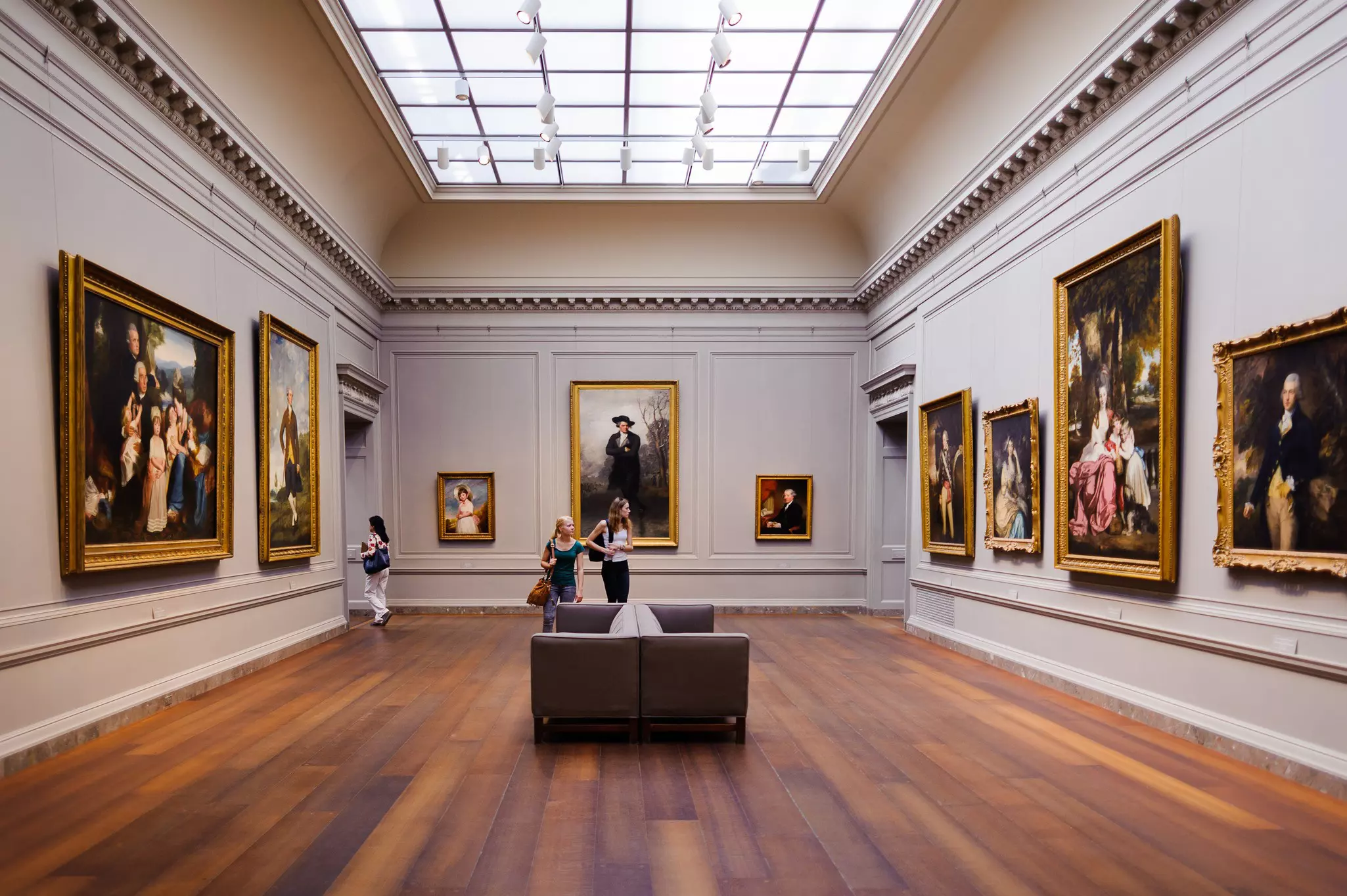 A gallery within an art museum showcasing large-scale portraits all framed in gold