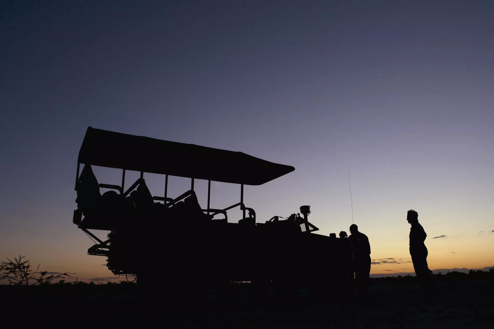 A four-wheel drive vehicle departing on a night safari at dusk.
