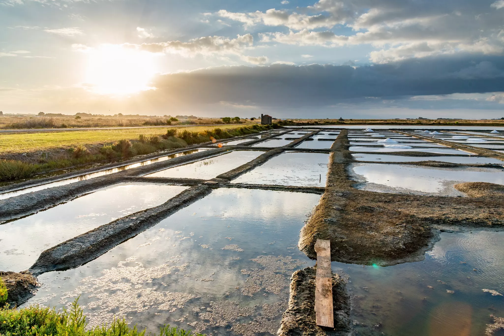 Salt marshes on the island of Noirmoutier in France. The sun rises on ponds, basins and salt piles. 