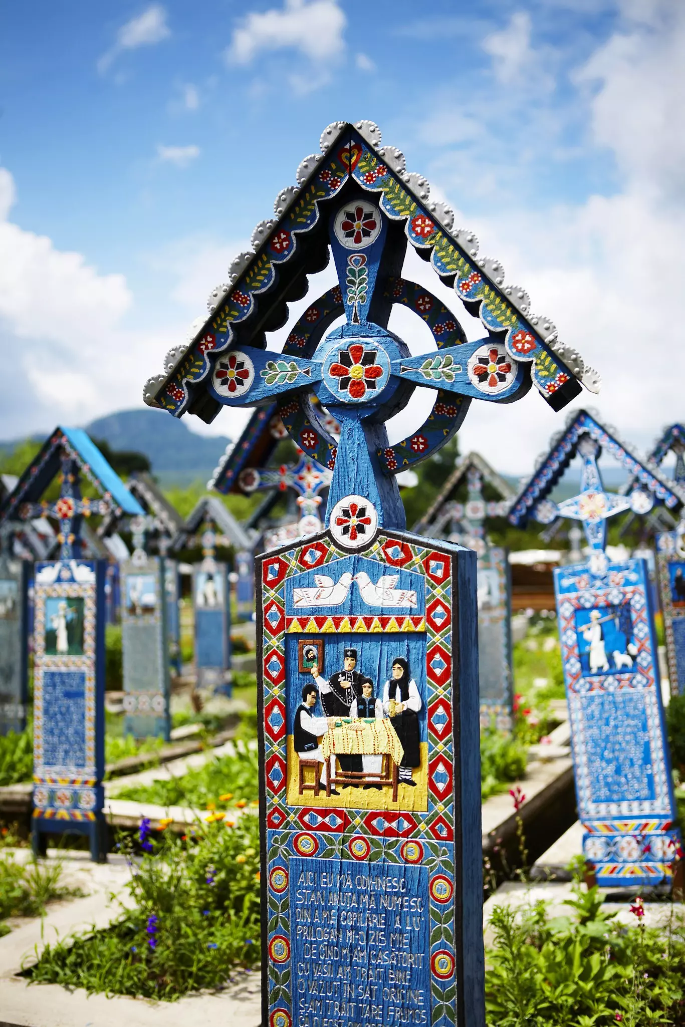 Tall wooden markers painted in blue with writing and other decoration indicate grave sites in Merry Cemetery, Săpânța, Romania