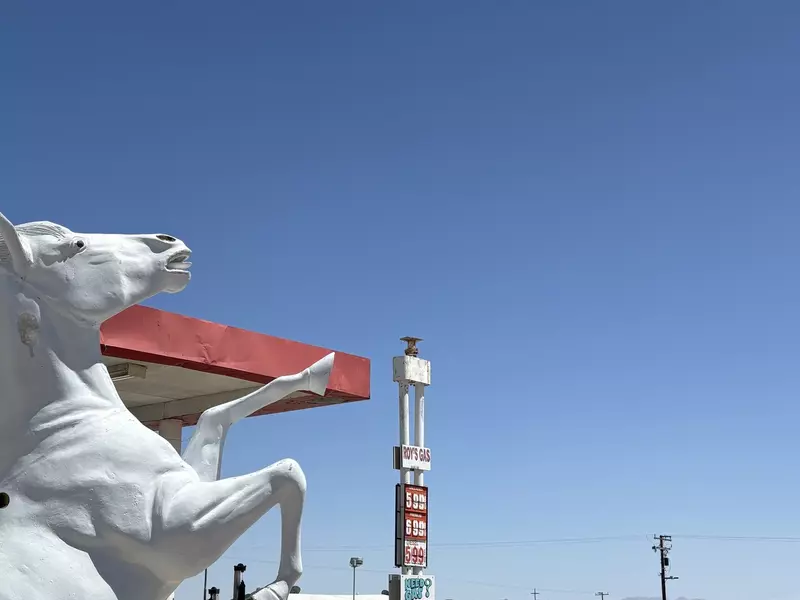 Man standing at a gas station taking photos
