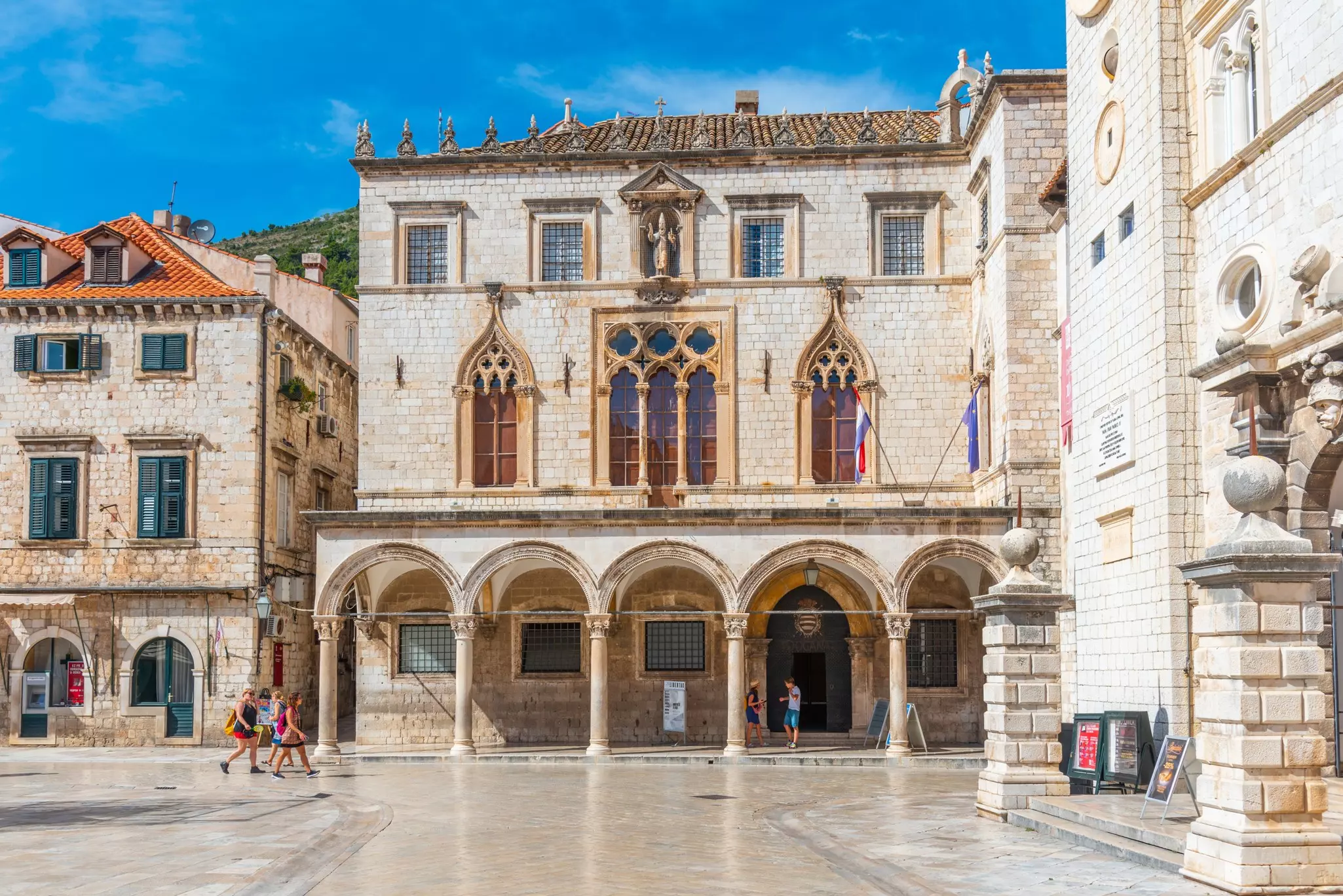 People walk by a large Gothic-Renaissance-style mansion