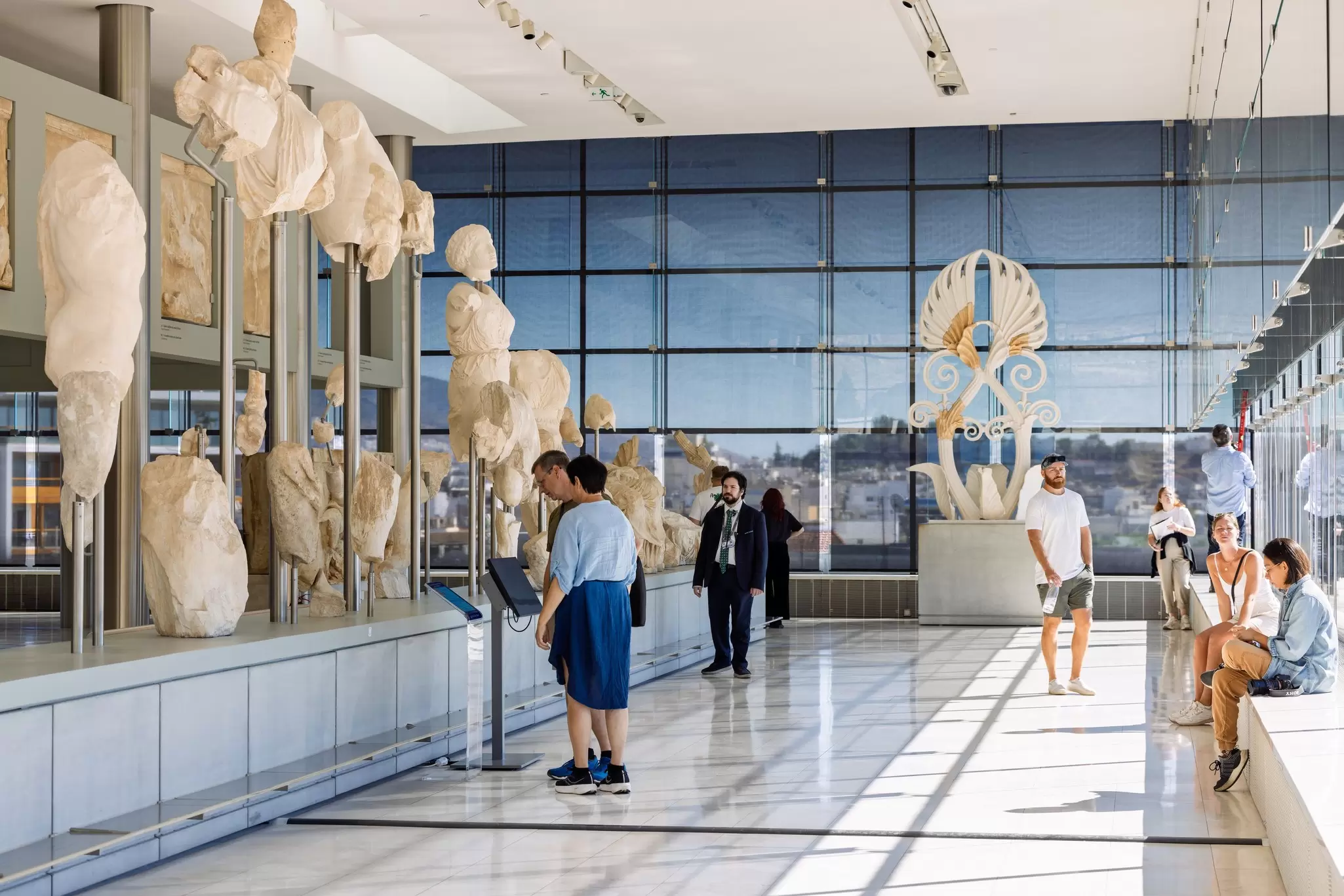 People looking at the artifacts displayed in the Parthenon Gallery inside the Acropolis Museum in Athens, Greece.