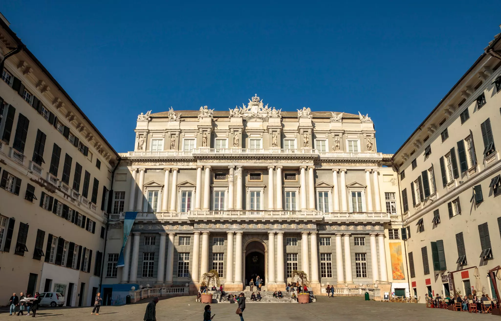 Tourists gather and take photos outside a 16th-century palace on a sunny day.