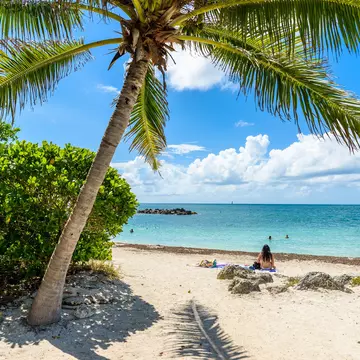 Key West, Florida - December 4, 2019:  People tan and rest on the sunny beach of Fort Zachary Taylor State Park in tropical Key West Florida USA