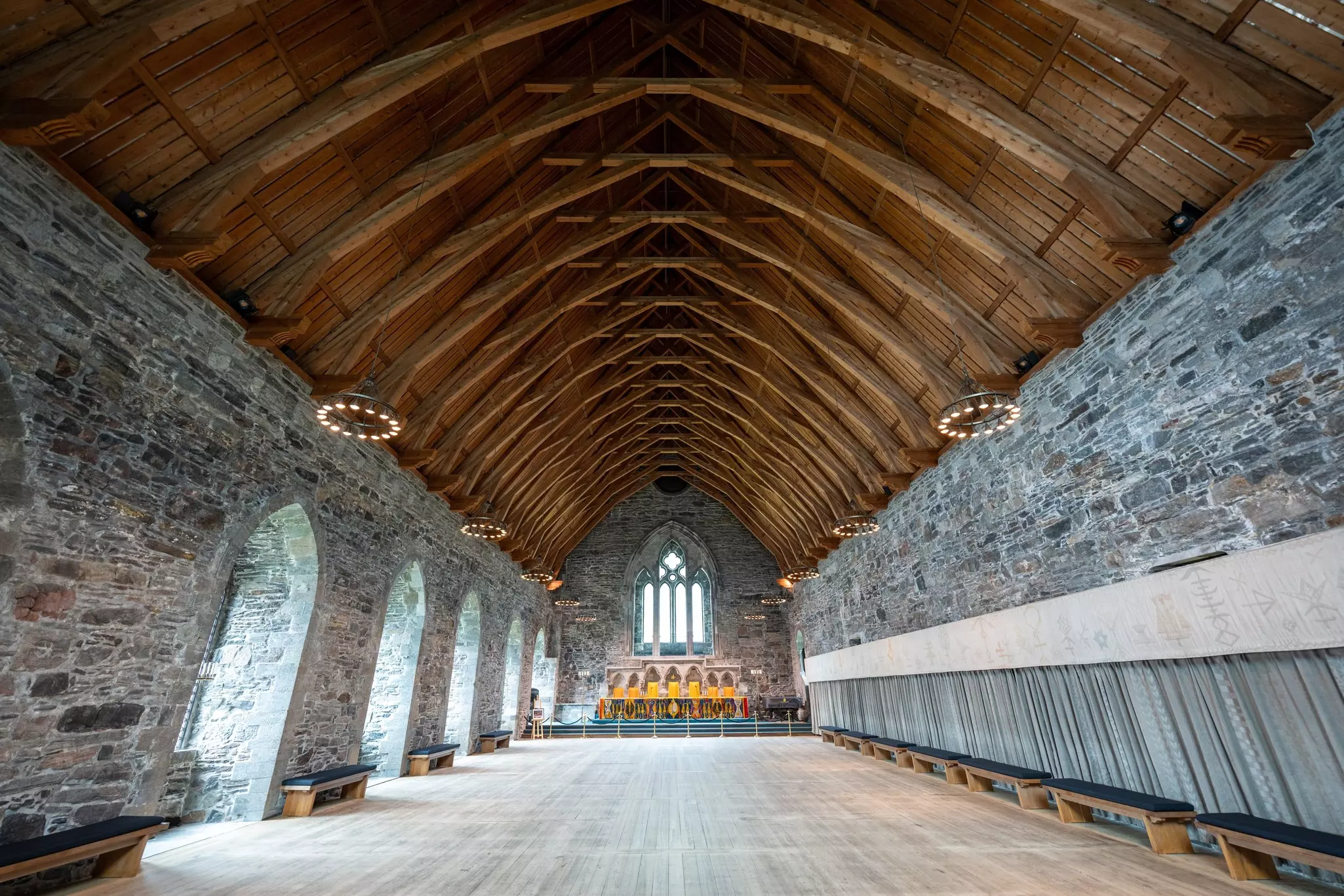 The stone walls and wooden beams in the interior of a large hall from the Middle Ages.