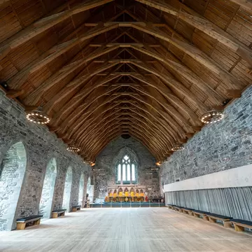 The stone walls and wooden beams in the interior of a large hall from the Middle Ages.