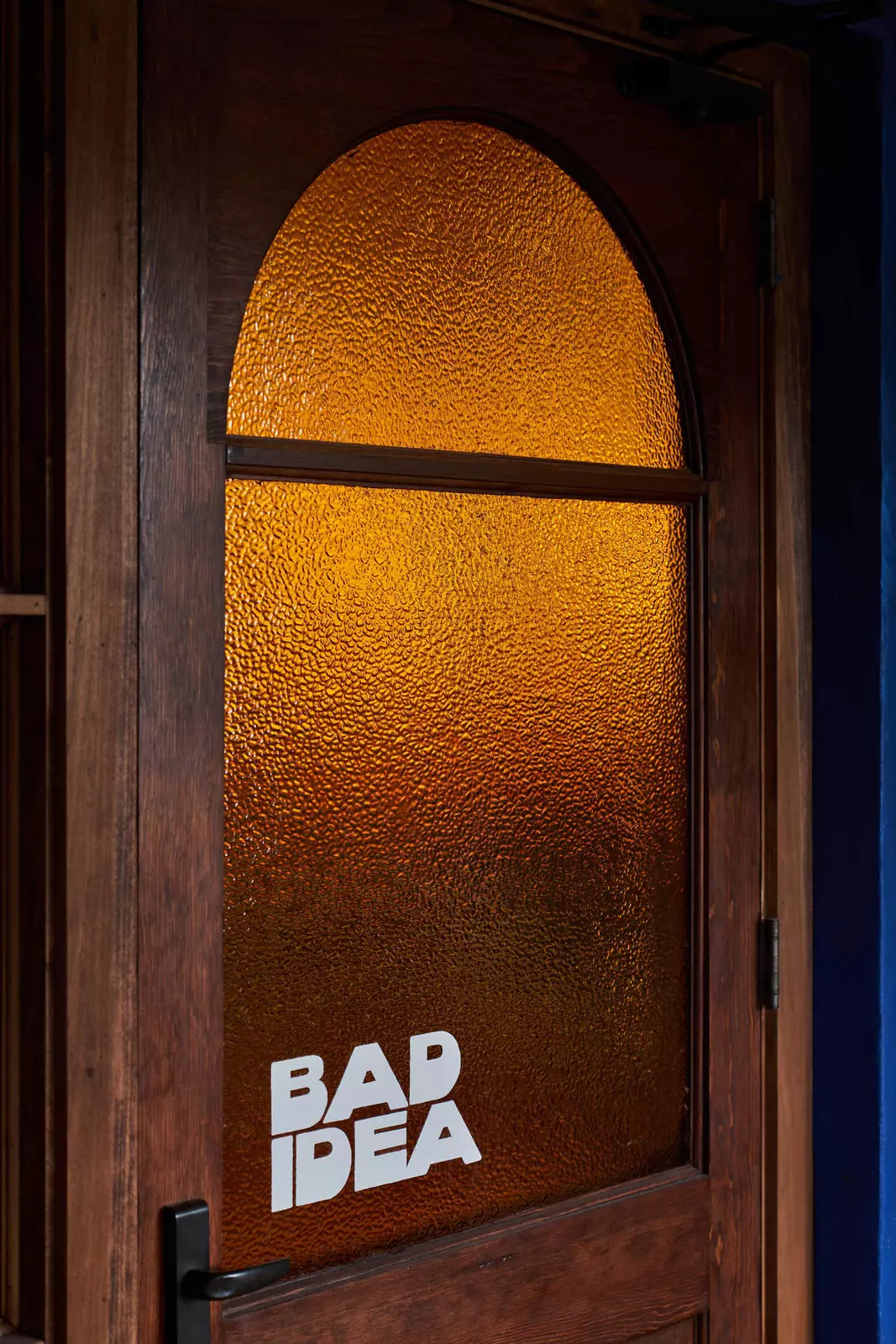 A wooden door with a frosted window that reads "Bad Idea"