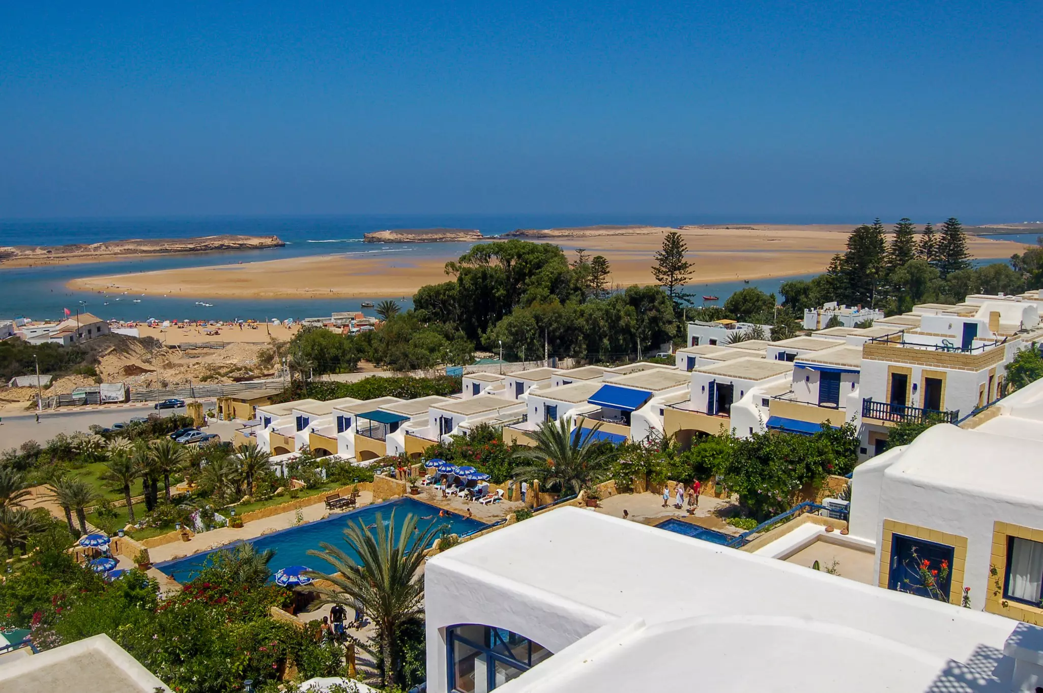 A view of the city of Oualidia in morocco, with the beach on the back and white stucco buildings on the foreground
