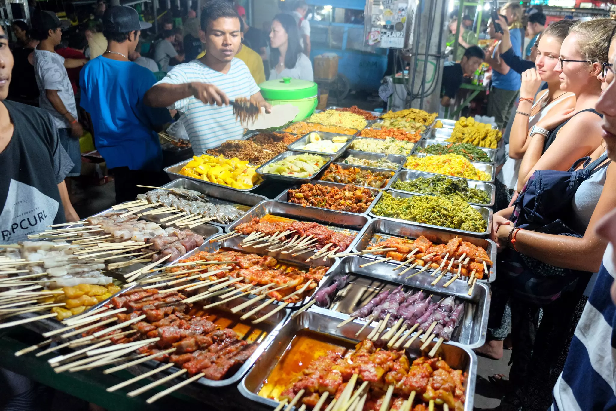 A vendor serving food at a street food stall at Trawangan Night Market. 